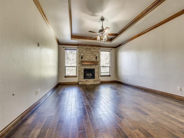 4109 Slate Bridge Rd, Edmond, OK 73034 - unfurnished living room featuring ceiling fan, a raised ceiling, crown molding, dark wood-style flooring, and a fireplace