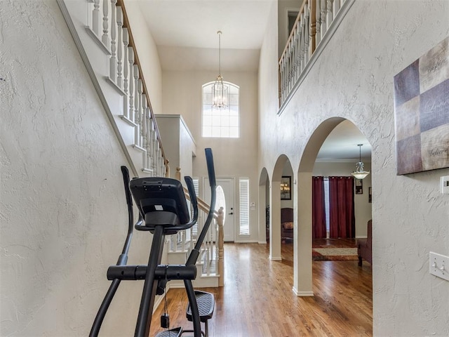 7300 NW 109th St, Oklahoma City, OK 73162 - exercise area with arched walkways, wood finished floors, a textured wall, a high ceiling, and a chandelier