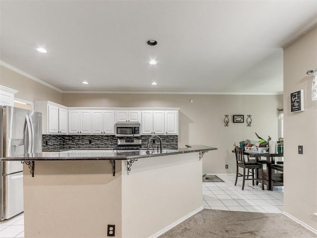 7300 NW 109th St, Oklahoma City, OK 73162 - kitchen with stainless steel appliances, a breakfast bar area, light tile patterned floors, white cabinetry, and ornamental molding