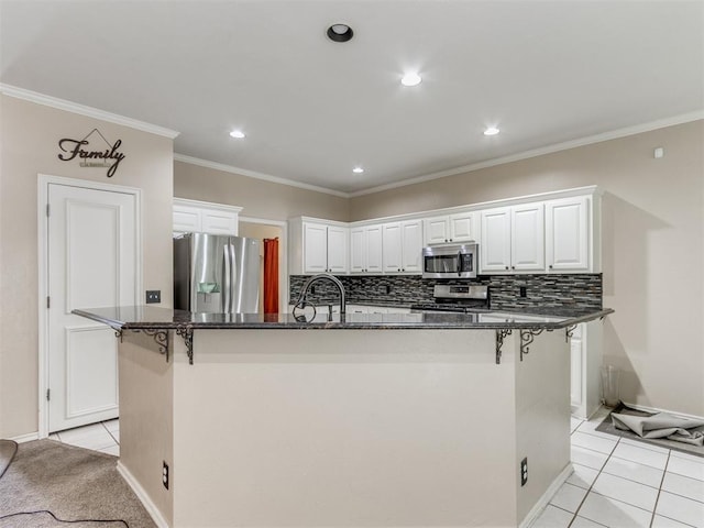 7300 NW 109th St, Oklahoma City, OK 73162 - kitchen featuring appliances with stainless steel finishes, white cabinetry, a breakfast bar area, a center island with sink, and backsplash