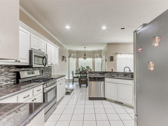 7300 NW 109th St, Oklahoma City, OK 73162 - kitchen featuring stainless steel appliances, white cabinetry, backsplash, light tile patterned floors, and crown molding