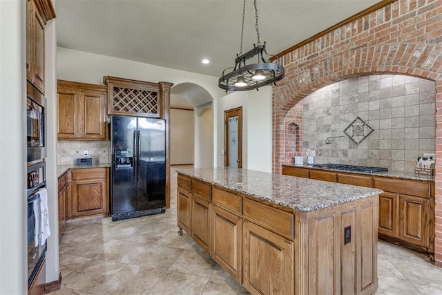 3000 Hampshire Ln, Oklahoma City, OK 73179 - kitchen with black appliances, arched walkways, a center island, backsplash, and light stone counters