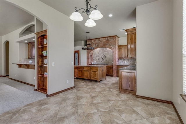 3000 Hampshire Ln, Oklahoma City, OK 73179 - kitchen featuring a chandelier, brown cabinetry, backsplash, and arched walkways