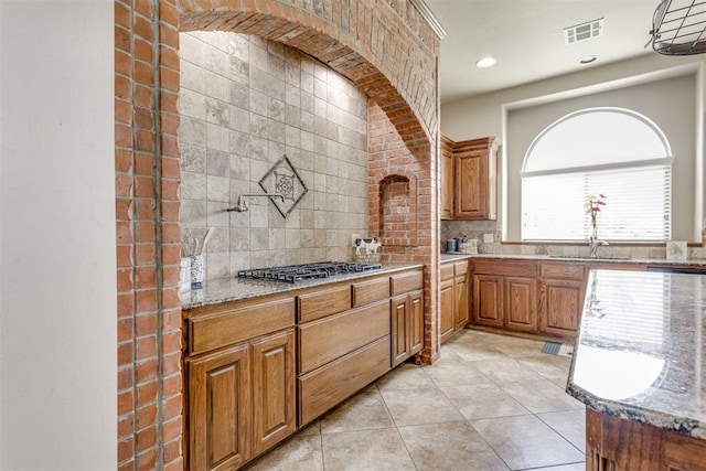 3000 Hampshire Ln, Oklahoma City, OK 73179 - kitchen featuring stainless steel gas cooktop, tasteful backsplash, light stone counters, brown cabinets, and recessed lighting