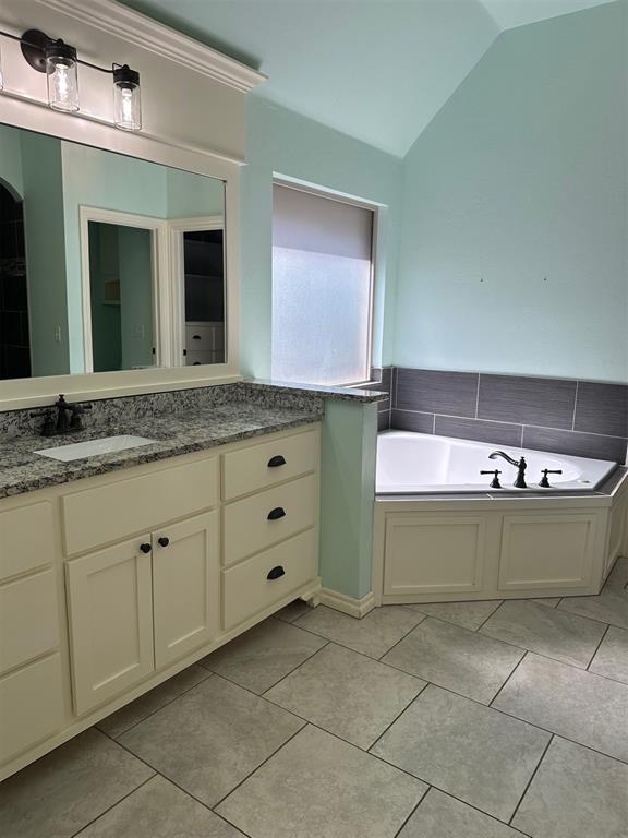 5024 SW 130th St, Oklahoma City, OK 73173 - full bath featuring vaulted ceiling, vanity, a garden tub, and tile patterned floors
