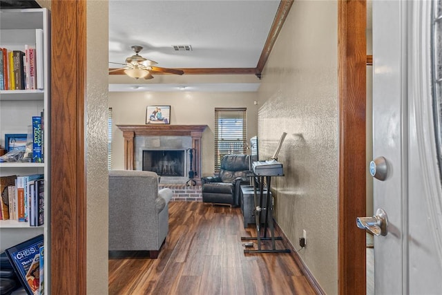 3008 Fairway Dr, Weatherford, OK 73096 - living area with a textured wall, ornamental molding, dark wood-style flooring, a ceiling fan, and a brick fireplace