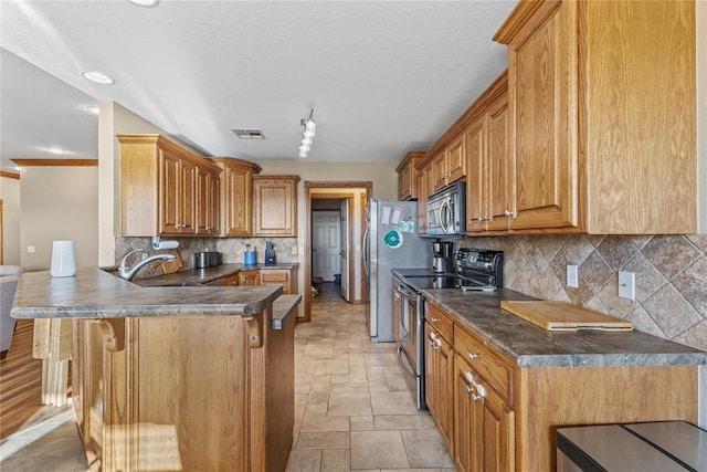 3008 Fairway Dr, Weatherford, OK 73096 - kitchen with appliances with stainless steel finishes, a peninsula, stone tile floors, a breakfast bar, and decorative backsplash