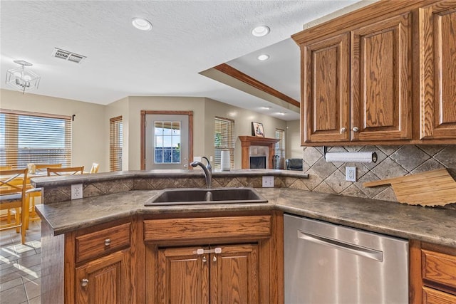 3008 Fairway Dr, Weatherford, OK 73096 - kitchen featuring stainless steel dishwasher, brown cabinets, dark countertops, recessed lighting, and a textured ceiling