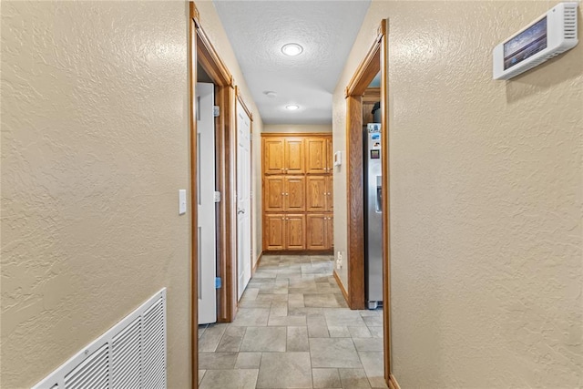 3008 Fairway Dr, Weatherford, OK 73096 - hall featuring stone finish flooring, a textured wall, a textured ceiling, and recessed lighting