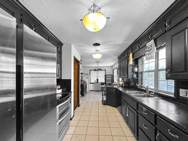 521 E Broadway St, Lexington, OK 73051 - kitchen with appliances with stainless steel finishes, dark countertops, light tile patterned floors, dark cabinetry, and a textured ceiling