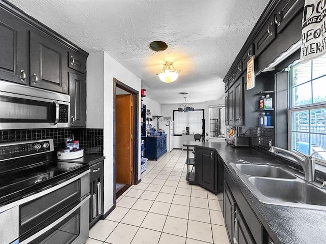 521 E Broadway St, Lexington, OK 73051 - kitchen featuring stainless steel appliances, dark cabinets, backsplash, light tile patterned floors, and a textured ceiling