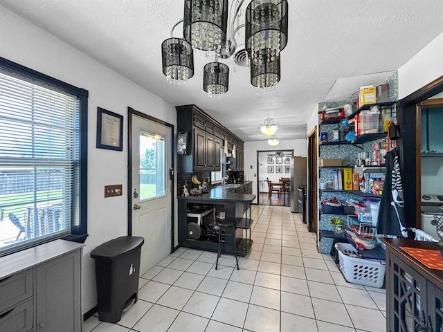 521 E Broadway St, Lexington, OK 73051 - kitchen with light tile patterned floors, a textured ceiling, a chandelier, freestanding refrigerator, and dark countertops