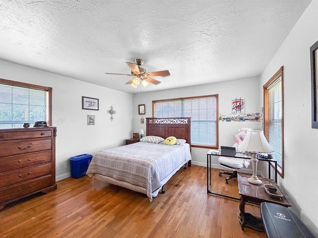 521 E Broadway St, Lexington, OK 73051 - bedroom with wood finished floors, multiple windows, a ceiling fan, and a textured ceiling