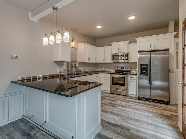 11300 N Pennsylvania Ave Unit 120, Oklahoma City, OK 73120 - kitchen with stainless steel appliances, a peninsula, white cabinetry, wood finished floors, and dark stone countertops