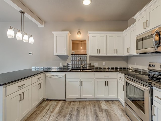 11300 N Pennsylvania Ave Unit 120, Oklahoma City, OK 73120 - kitchen with stainless steel appliances, a peninsula, white cabinets, light wood-style flooring, and pendant lighting