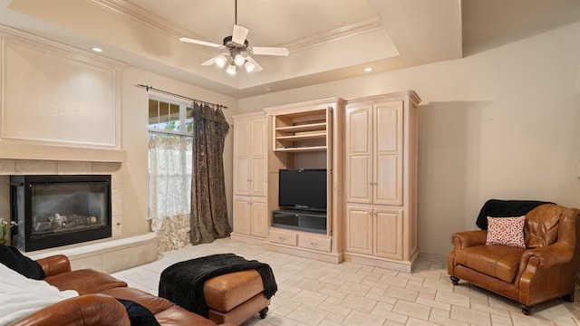 704 Capri Pl, Edmond, OK 73034 - living room with a tray ceiling, a tiled fireplace, ceiling fan, ornamental molding, and recessed lighting