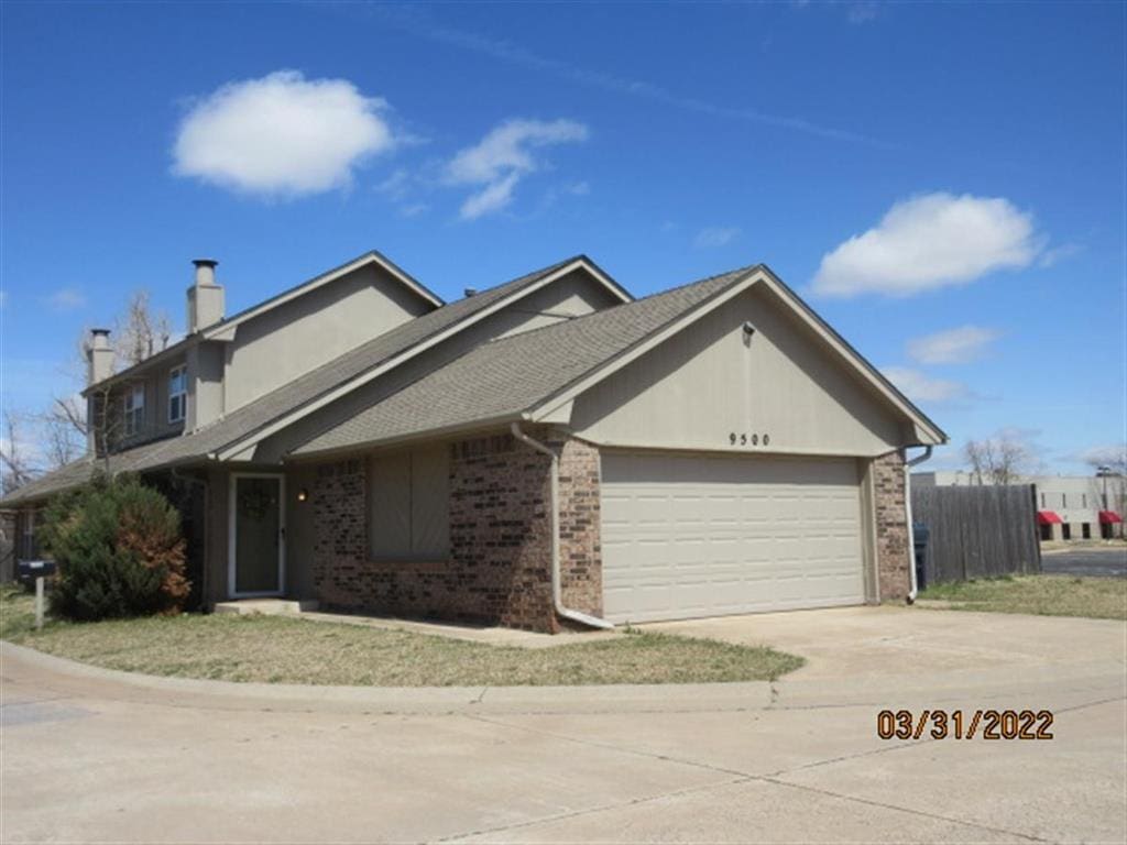 9500 Berkley Ter, Oklahoma City, OK 73162 - view of front of home with driveway, a chimney, a garage, and brick siding