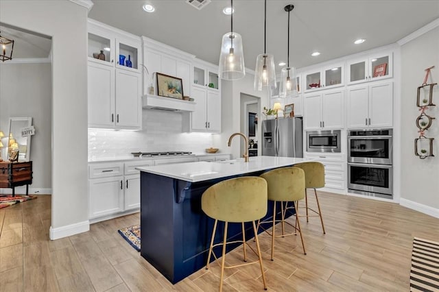 2033 Marsala Dr, Edmond, OK 73034 - kitchen featuring stainless steel appliances, ornamental molding, light wood-style flooring, light countertops, and tasteful backsplash