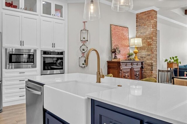 2033 Marsala Dr, Edmond, OK 73034 - kitchen featuring appliances with stainless steel finishes, light countertops, pendant lighting, light wood-style floors, and white cabinets