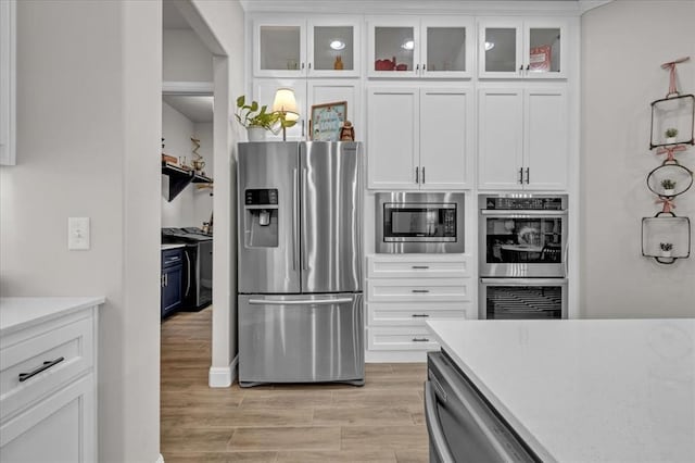 2033 Marsala Dr, Edmond, OK 73034 - kitchen with appliances with stainless steel finishes, light countertops, white cabinetry, and light wood-type flooring