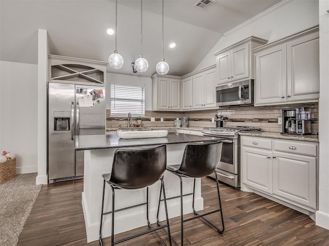 5112 NW 163rd St, Edmond, OK 73013 - kitchen featuring appliances with stainless steel finishes, decorative backsplash, a kitchen bar, vaulted ceiling, and a kitchen island