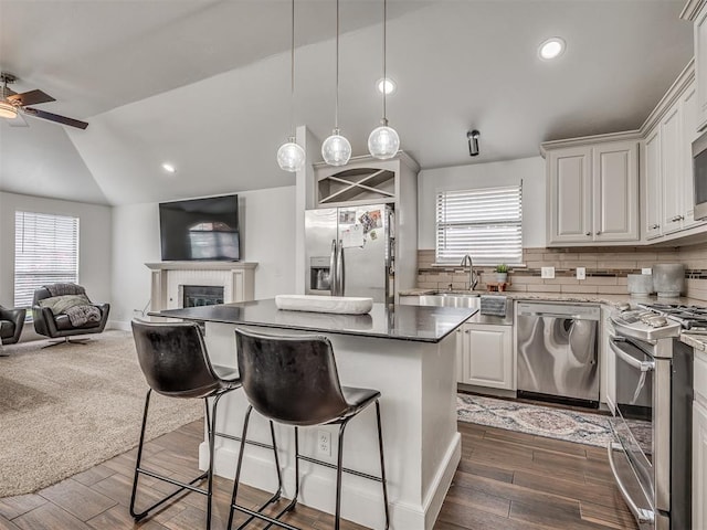 5112 NW 163rd St, Edmond, OK 73013 - kitchen featuring appliances with stainless steel finishes, open floor plan, vaulted ceiling, a breakfast bar, and a center island