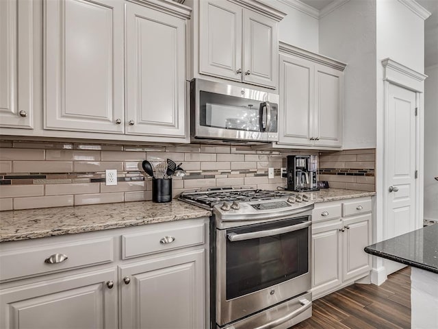 5112 NW 163rd St, Edmond, OK 73013 - kitchen featuring appliances with stainless steel finishes, ornamental molding, decorative backsplash, dark wood finished floors, and light stone counters