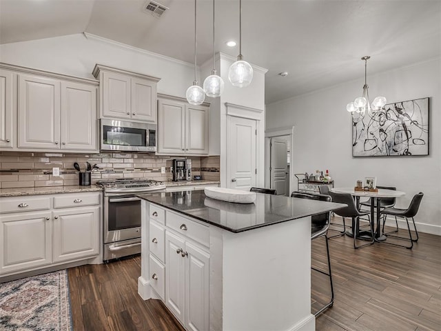 5112 NW 163rd St, Edmond, OK 73013 - kitchen featuring stainless steel appliances, backsplash, a kitchen island, dark wood-style floors, and a kitchen breakfast bar