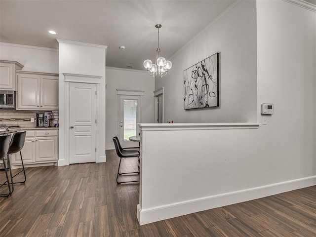 5112 NW 163rd St, Edmond, OK 73013 - kitchen featuring crown molding, stainless steel microwave, dark wood-type flooring, tasteful backsplash, and light countertops