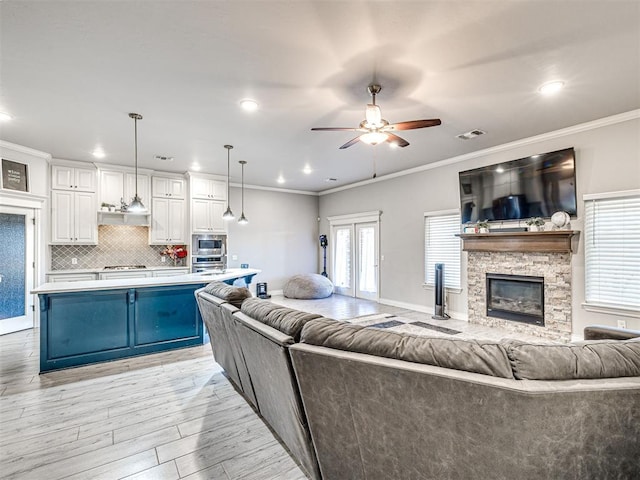 917 NE 34th Ter, Moore, OK 73160 - living room with a ceiling fan, light wood-style flooring, crown molding, a stone fireplace, and recessed lighting