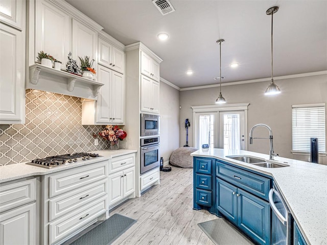 917 NE 34th Ter, Moore, OK 73160 - kitchen featuring stainless steel appliances, white cabinetry, blue cabinetry, backsplash, and decorative light fixtures