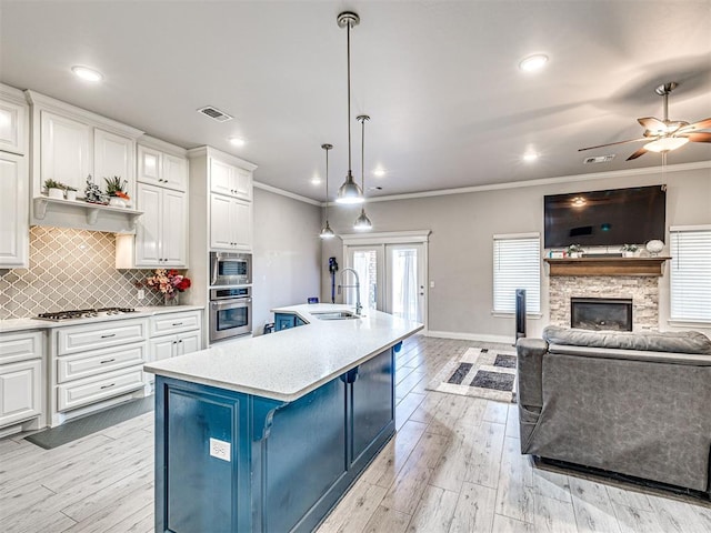 917 NE 34th Ter, Moore, OK 73160 - kitchen featuring stainless steel appliances, crown molding, light countertops, open floor plan, and white cabinets