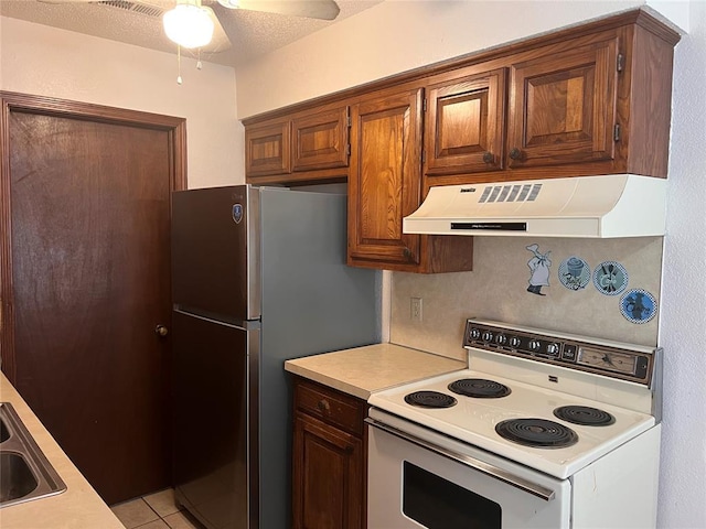 8300 NW 10th St Unit 140, Oklahoma City, OK 73127 - kitchen with white electric range, extractor fan, light countertops, freestanding refrigerator, and a ceiling fan