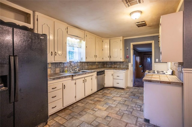 423 N Missouri St, Weatherford, OK 73669 - kitchen featuring black fridge, tasteful backsplash, stainless steel dishwasher, and tile counters