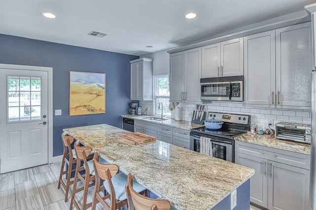 1621 NW 18th St, Oklahoma City, OK 73106 - kitchen featuring stainless steel appliances, gray cabinetry, healthy amount of natural light, a kitchen island, and recessed lighting
