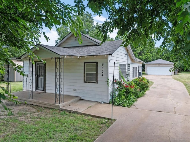 4504 N Grove Ave, Warr Acres, OK 73122 - bungalow-style home featuring a porch, a shingled roof, an outdoor structure, a detached garage, and a front lawn