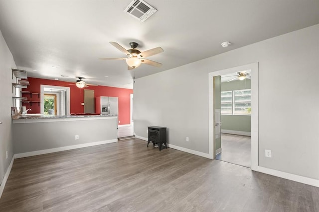 4504 N Grove Ave, Warr Acres, OK 73122 - unfurnished living room featuring a wood stove, a ceiling fan, and wood finished floors