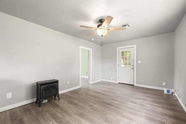 4504 N Grove Ave, Warr Acres, OK 73122 - spare room featuring a wood stove, a ceiling fan, and wood finished floors
