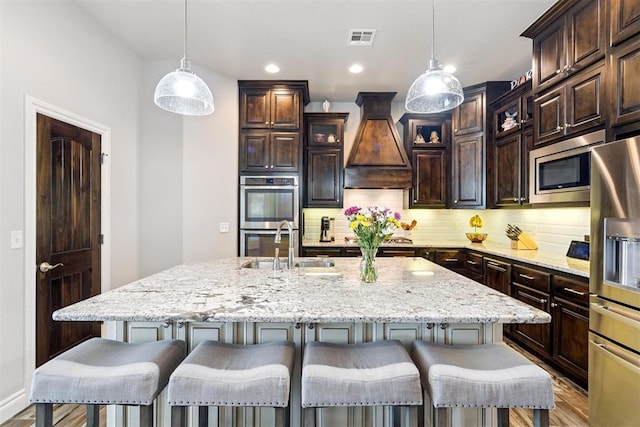 12505 Shady Gln, Choctaw, OK 73020 - kitchen featuring appliances with stainless steel finishes, custom exhaust hood, wood finished floors, tasteful backsplash, and recessed lighting