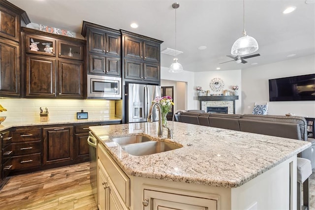 12505 Shady Gln, Choctaw, OK 73020 - kitchen featuring stainless steel appliances, light wood-style flooring, a ceiling fan, open floor plan, and a center island with sink