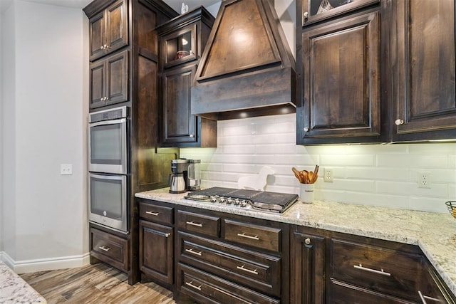 12505 Shady Gln, Choctaw, OK 73020 - kitchen featuring appliances with stainless steel finishes, custom exhaust hood, backsplash, and light wood-type flooring