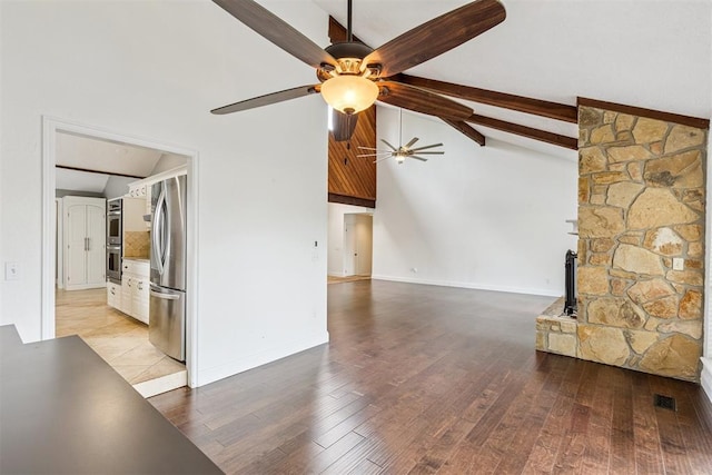 2416 Chimney Hill Ct, Edmond, OK 73034 - unfurnished living room with ceiling fan, beamed ceiling, a wood stove, light wood-type flooring, and high vaulted ceiling