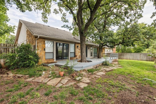2416 Chimney Hill Ct, Edmond, OK 73034 - rear view of house featuring stone siding, a fenced backyard, a shingled roof, and a wooden deck