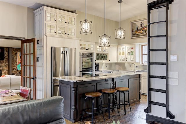 4225 Red Bud Pl, Edmond, OK 73013 - kitchen featuring appliances with stainless steel finishes, a kitchen breakfast bar, a kitchen island, decorative light fixtures, and light stone counters