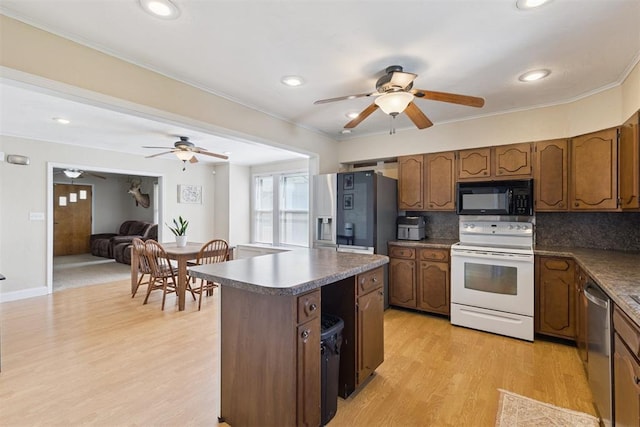 1623 W Washington Ave, Guthrie, OK 73044 - kitchen featuring stainless steel appliances, a ceiling fan, dark countertops, ornamental molding, and light wood-style flooring