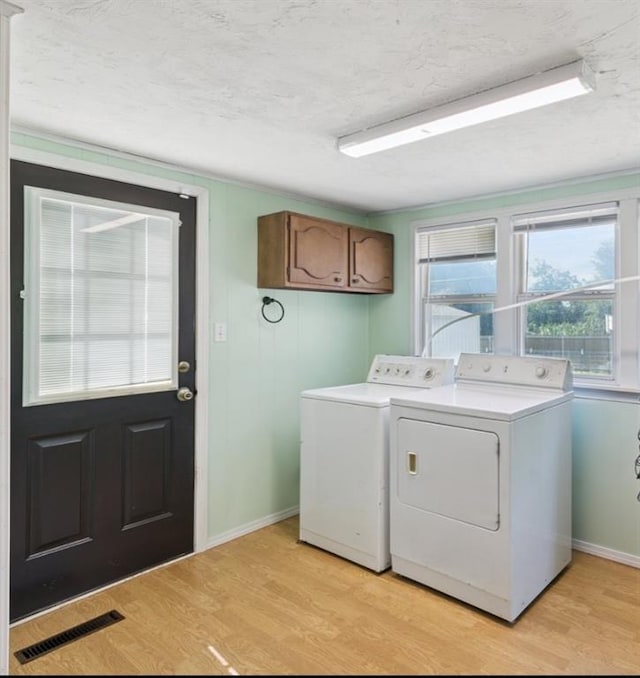 1623 W Washington Ave, Guthrie, OK 73044 - laundry area with washer and clothes dryer, cabinet space, light wood-style flooring, and a textured ceiling