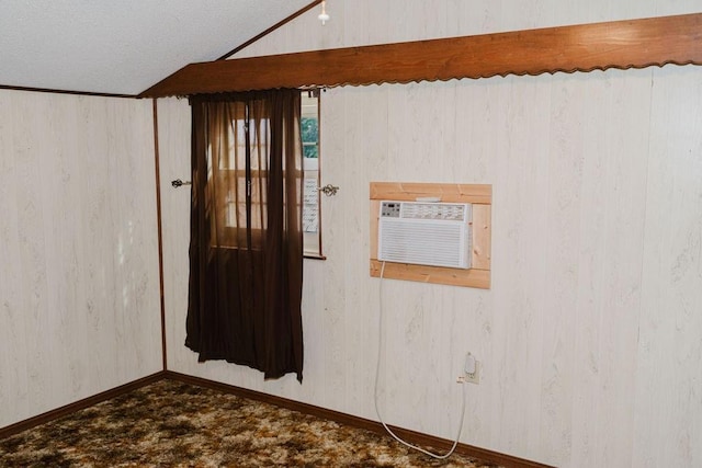 503 N Sheb Wooley Ave, Erick, OK 73645 - unfurnished room with a wall mounted AC, vaulted ceiling, and dark colored carpet