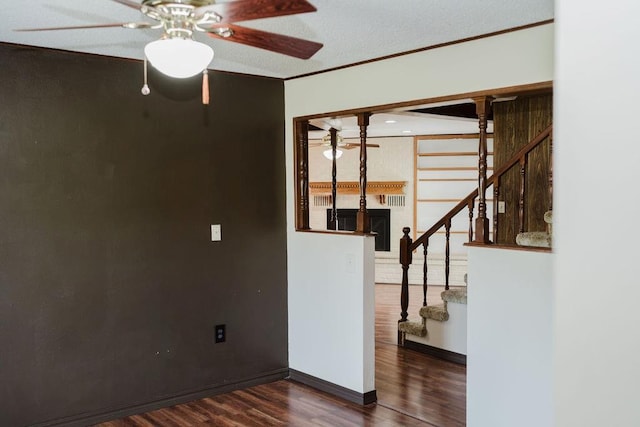 503 N Sheb Wooley Ave, Erick, OK 73645 - unfurnished room featuring stairway, a ceiling fan, wood finished floors, a fireplace, and ornamental molding
