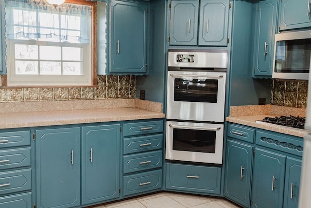 503 N Sheb Wooley Ave, Erick, OK 73645 - kitchen with stainless steel appliances, tasteful backsplash, light countertops, light tile patterned floors, and blue cabinets