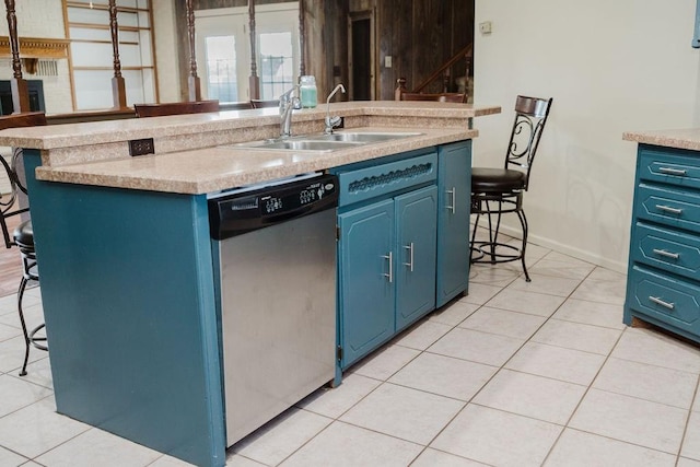 503 N Sheb Wooley Ave, Erick, OK 73645 - kitchen with dishwasher, blue cabinetry, a breakfast bar area, light tile patterned flooring, and a center island with sink